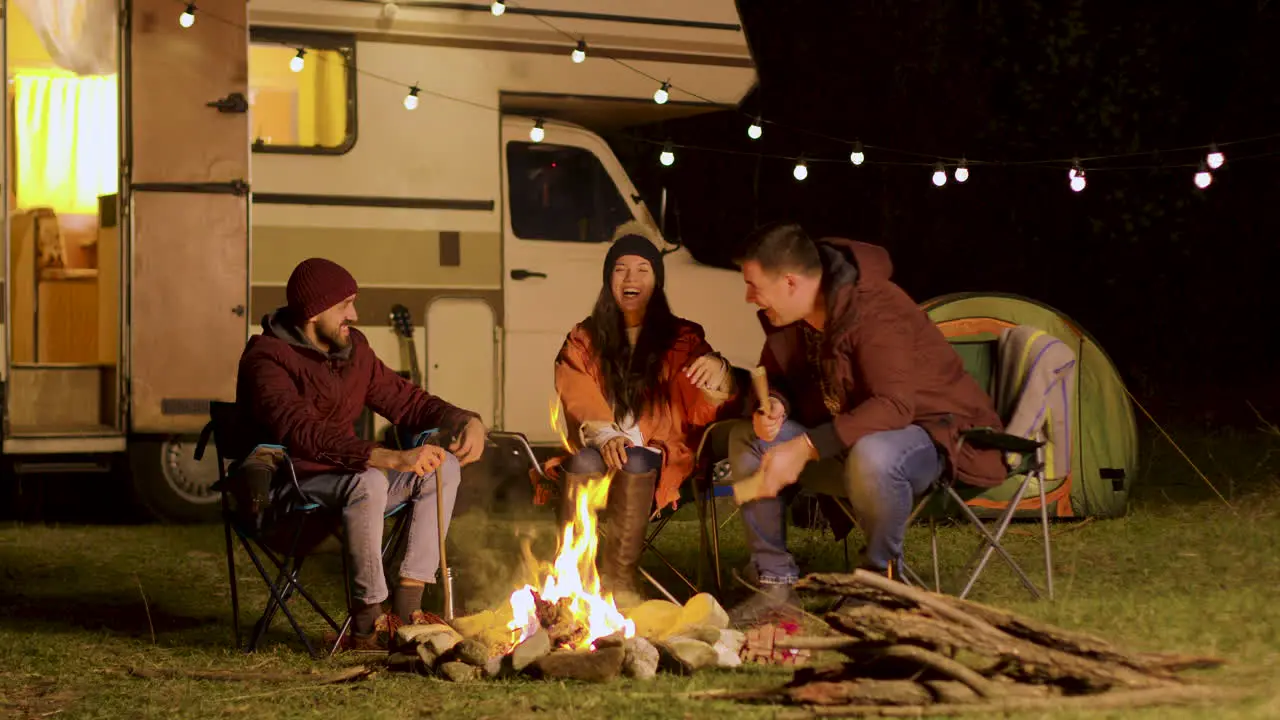 Group of close friends laughing together around camp fire