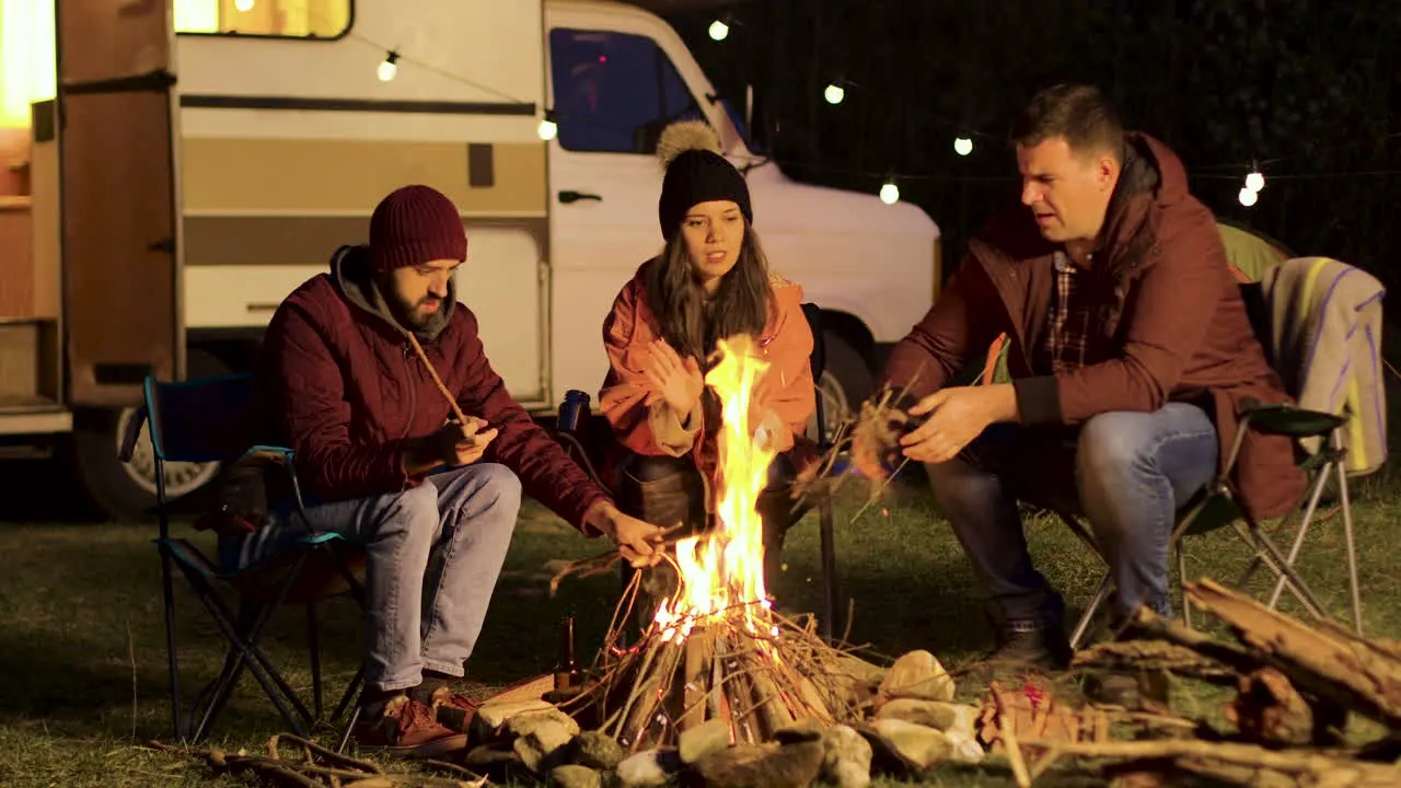 Girl warming up her hands while her friend making the fire stronger