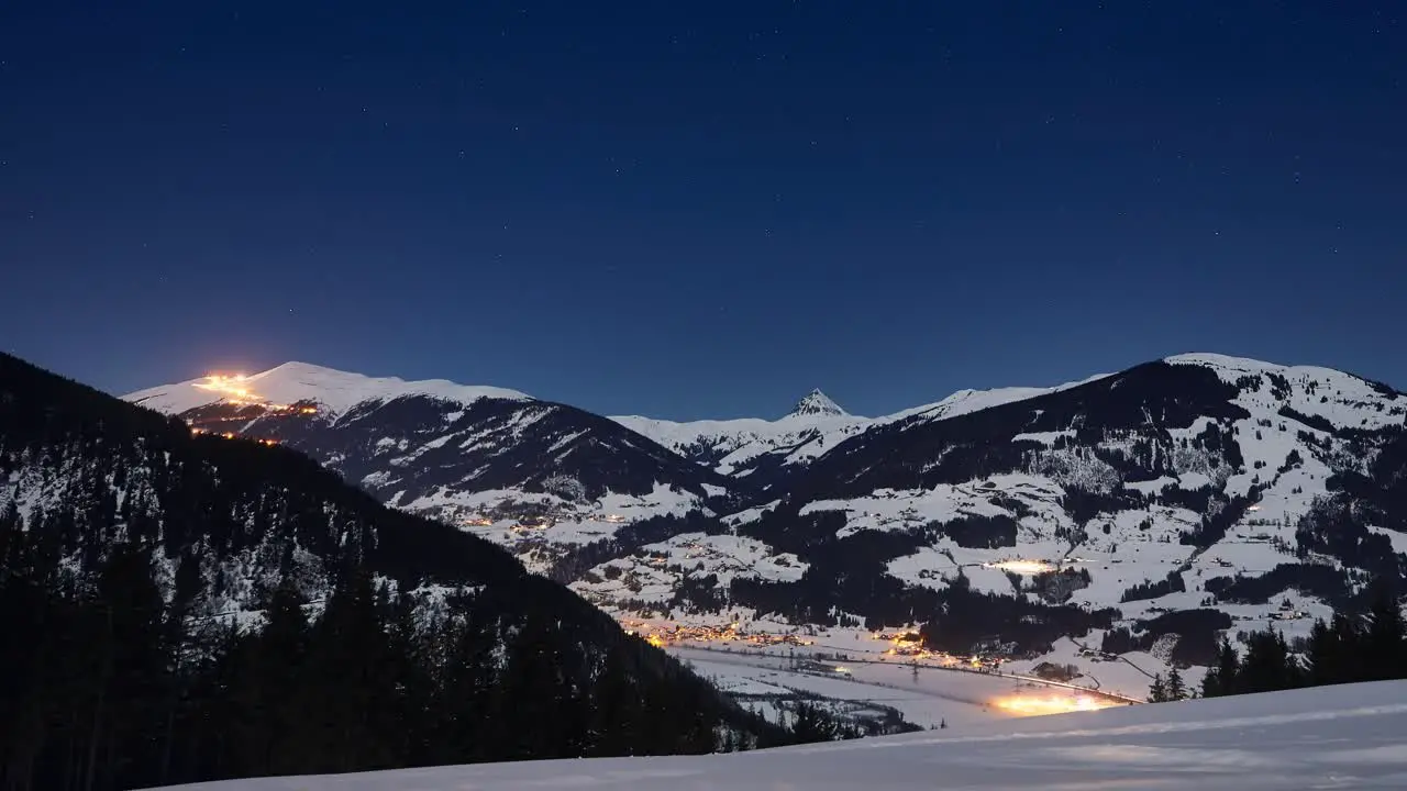 Time lapse of a zoom out mountain panorama of a snowy ski resort and starry sky