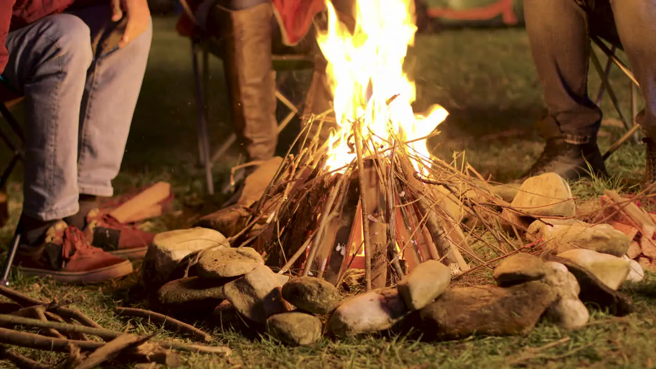 Handheld footage of man making camp fire for his friends in a cold night