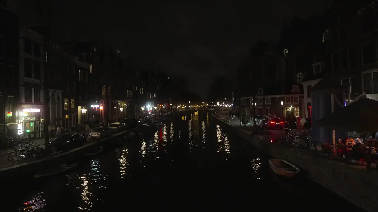 Amsterdam city canal during night time pedestrians walking around busy city area