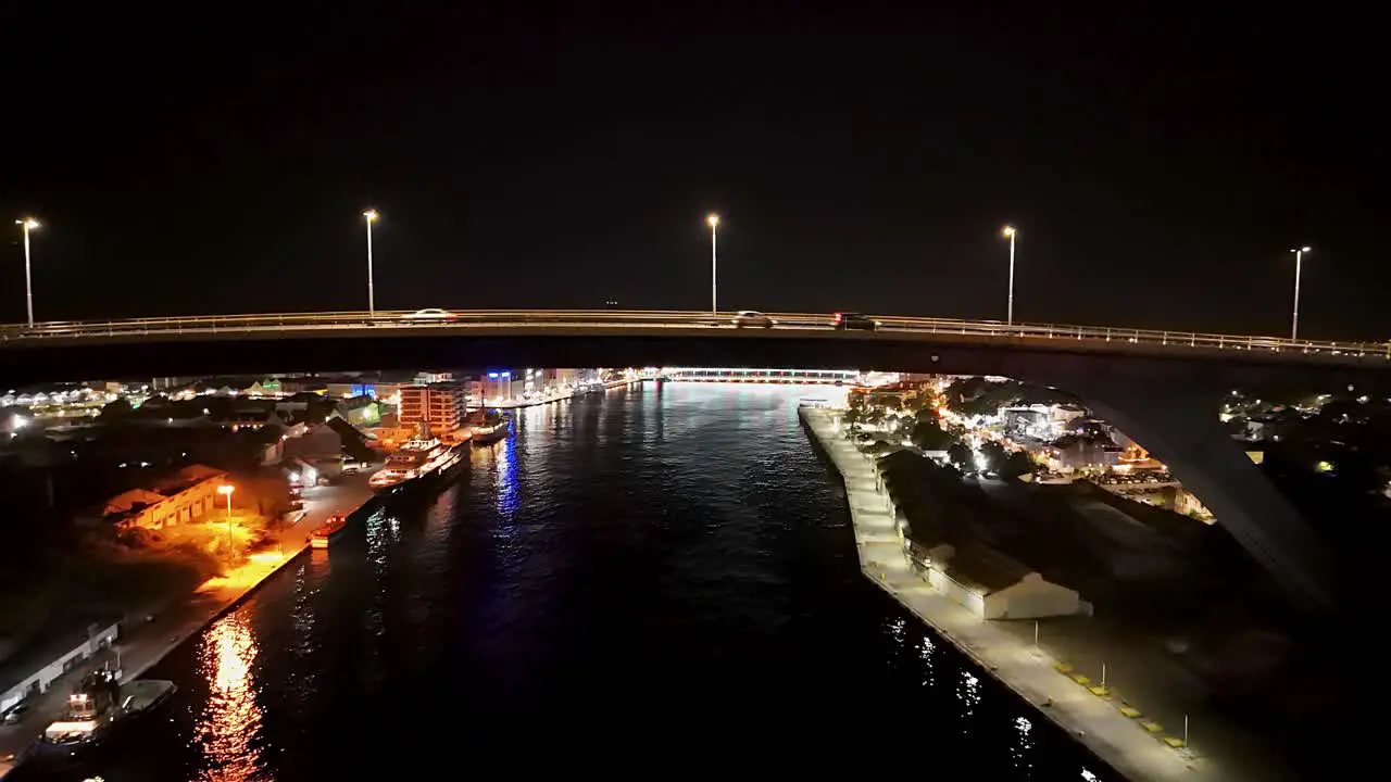 Queen Juliana bridge illuminated at night as drone rises above Handelskade