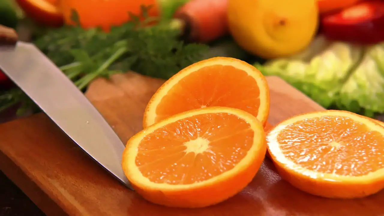 Orange slice fallen on chopping board with kitchen knife and other cutting pieces prepared for fresh salad