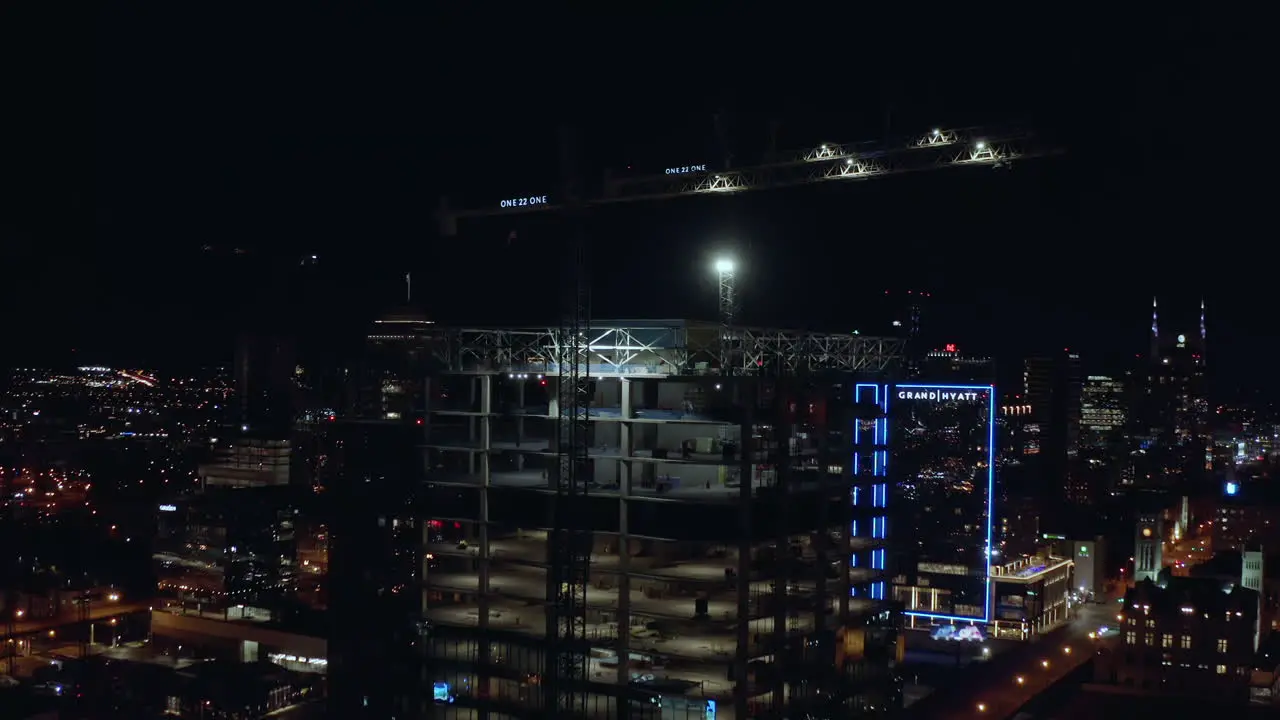 Night city aerial of building tower under construction with cranes on top 4K