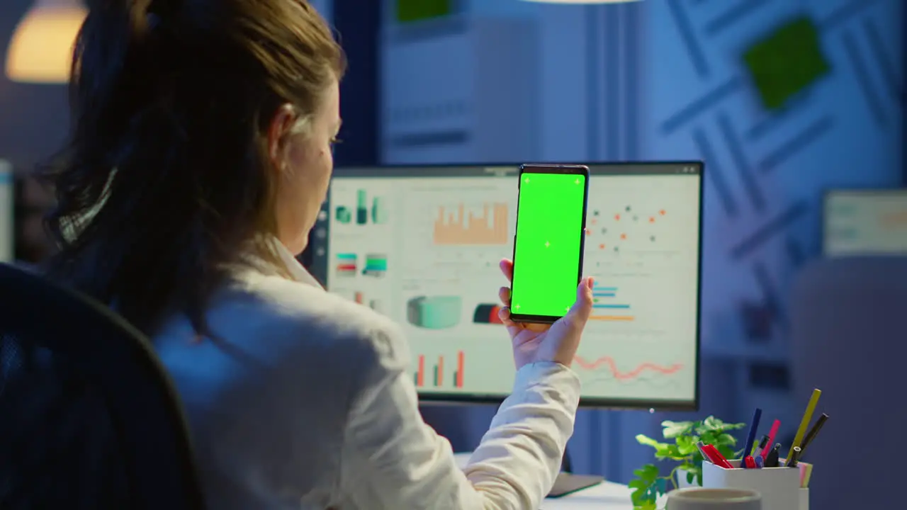 Back view of business woman looking at smartphone with green screen