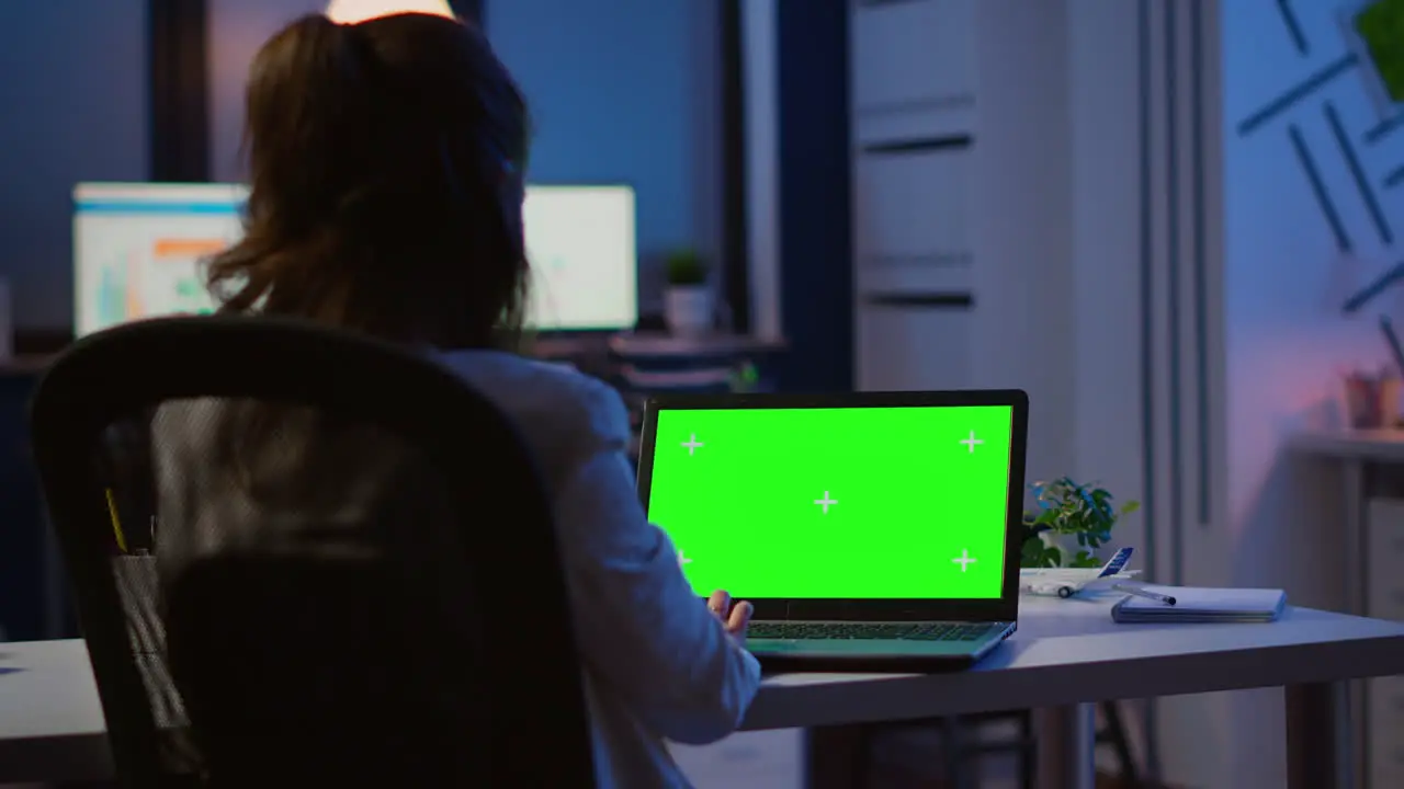 Back view of business woman looking at green screen laptop