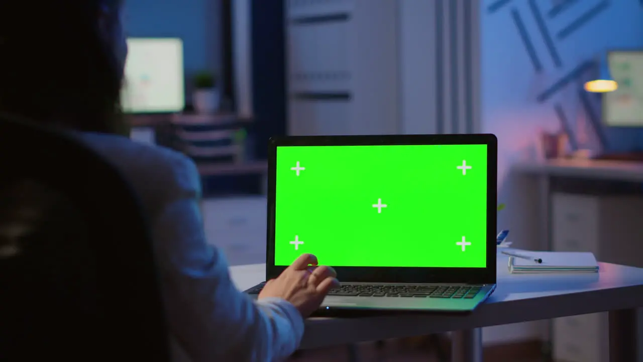 Woman looking at laptop with green mockup during night time