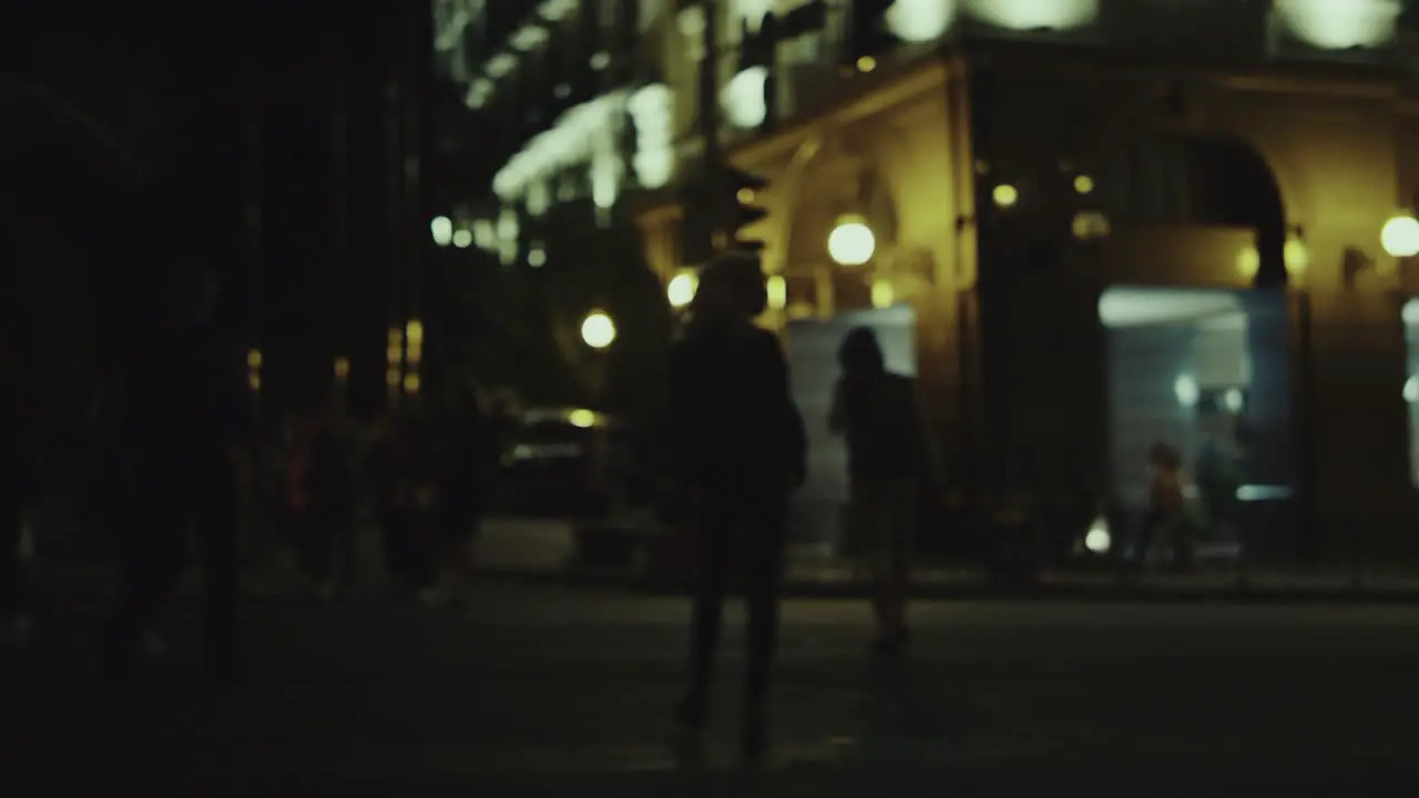 Woman crossing street night on crosswalk at city lights downtown