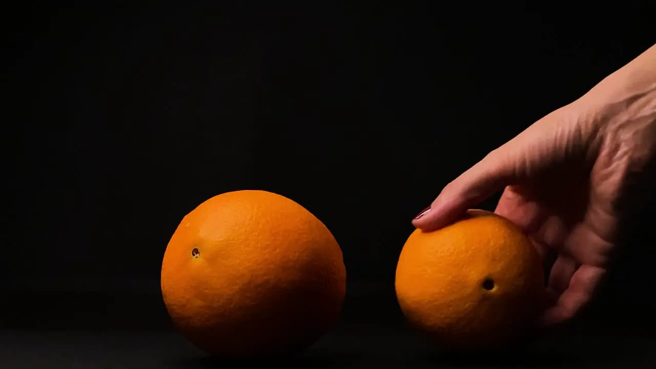 Woman hand pick up orange fruit black background