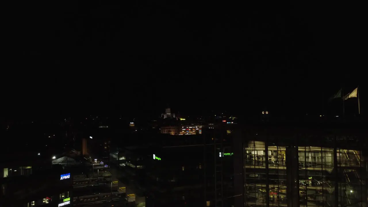 Black night aerial rises over illuminated buildings downtown Helsinki