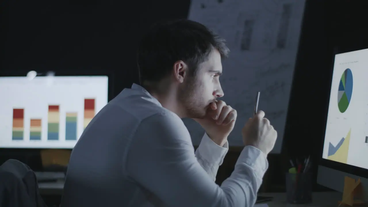 Thoughtful business analyst researching graphs and charts in night office