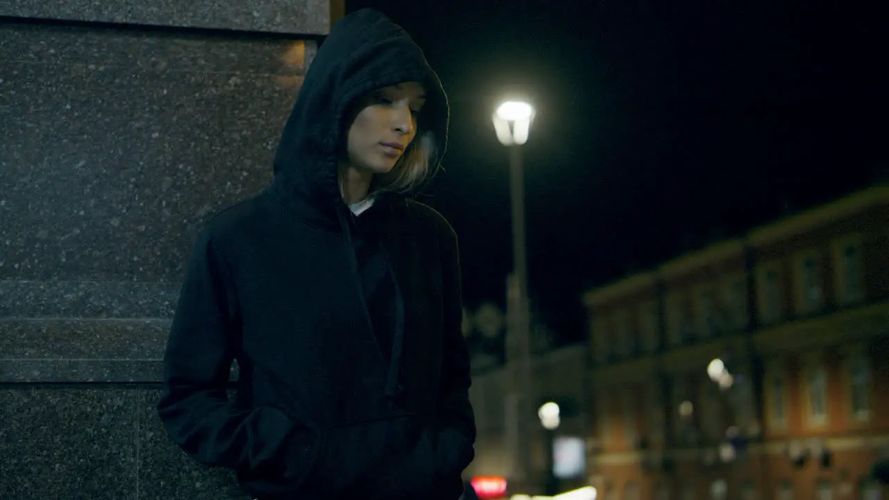 Mysterious woman standing city lights wearing hoodie at night street