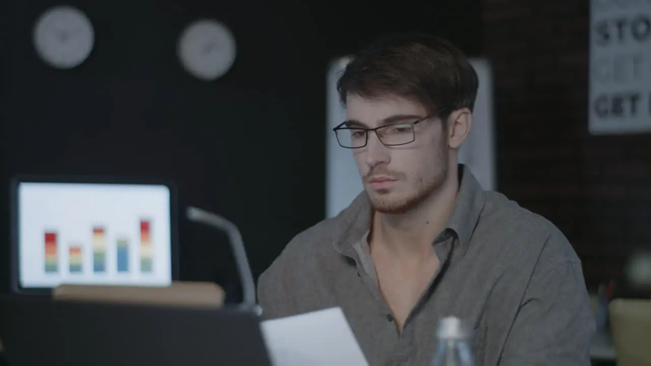 Thoughtful business man working with document near computer in dark office