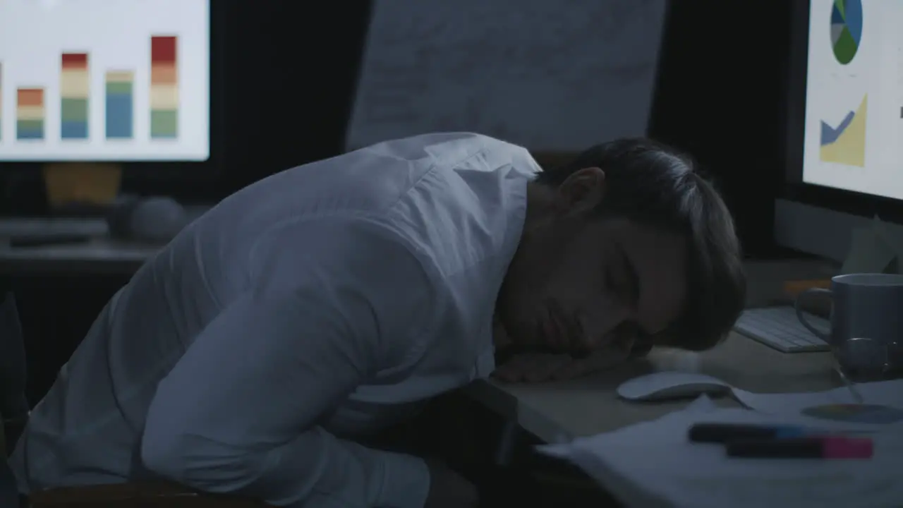 Tired business man sleeping on desk front computer screen in night office