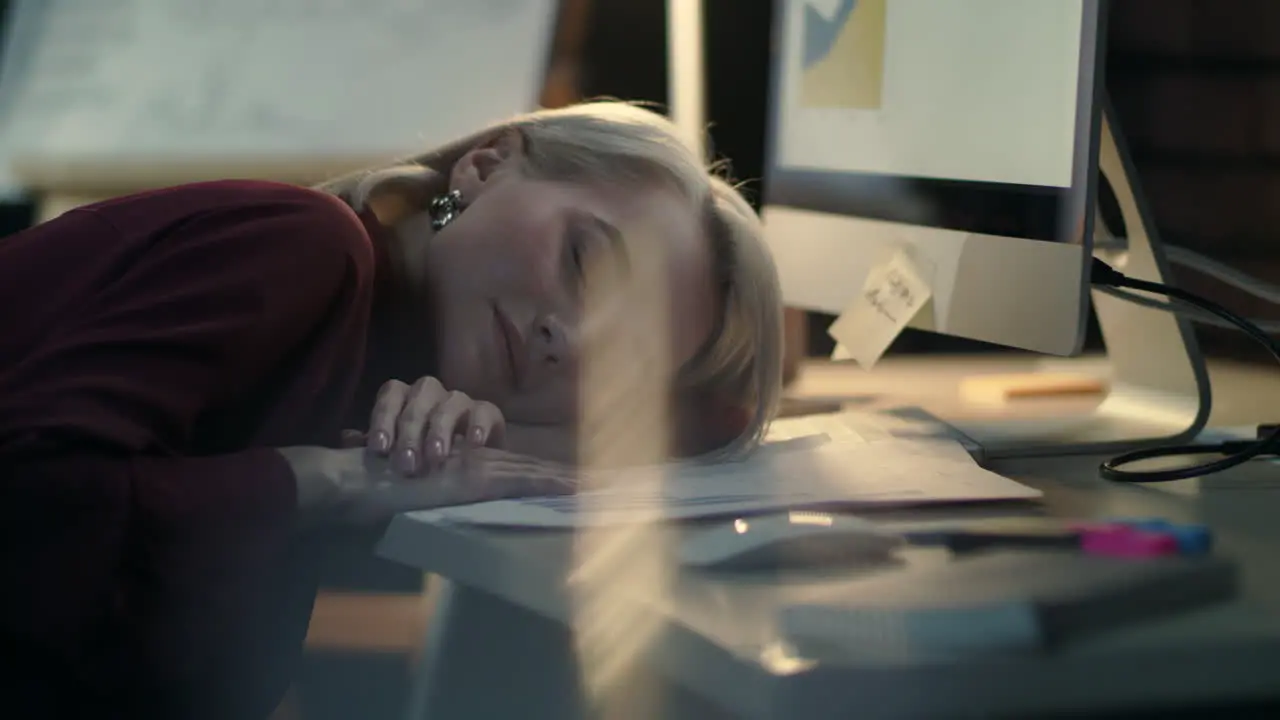 Exhausted business woman lying down on computer table at night work in office