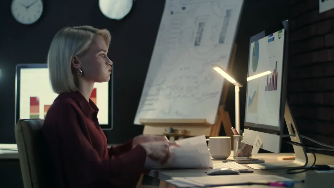 Focused business woman checking financial reports on computer in dark office