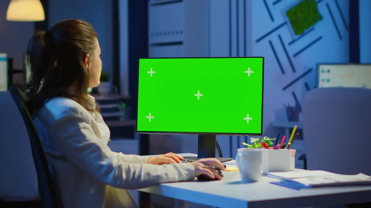 Businesswoman looking at green screen monitor of computer