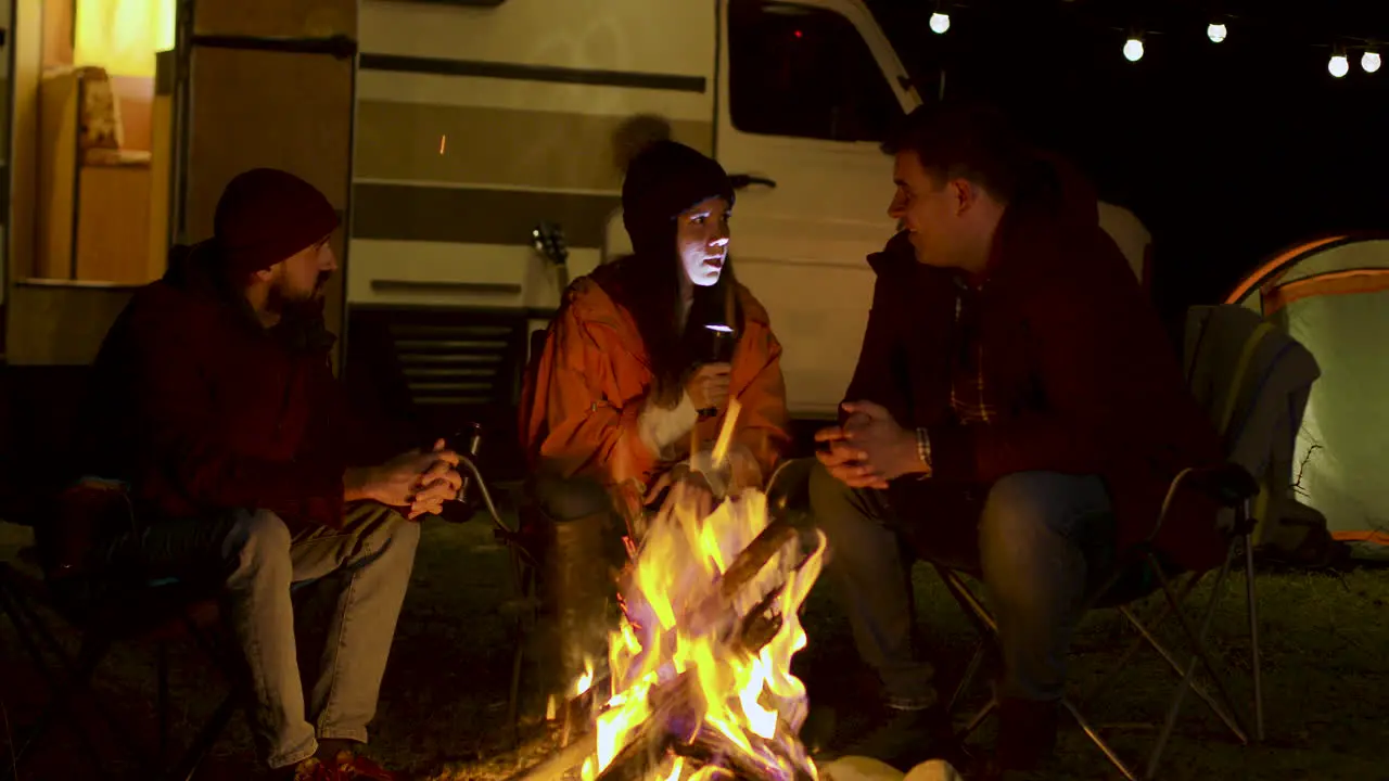 Girl telling a scary story to her friends around camp fire