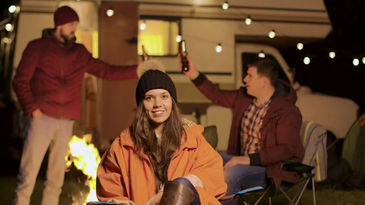 Girl sitting on a camping chair in a cold night of autumn