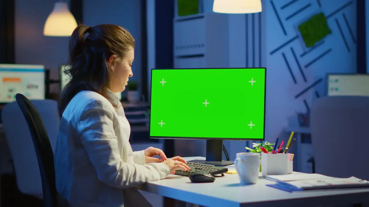 Woman looking at computer with chroma key during night time