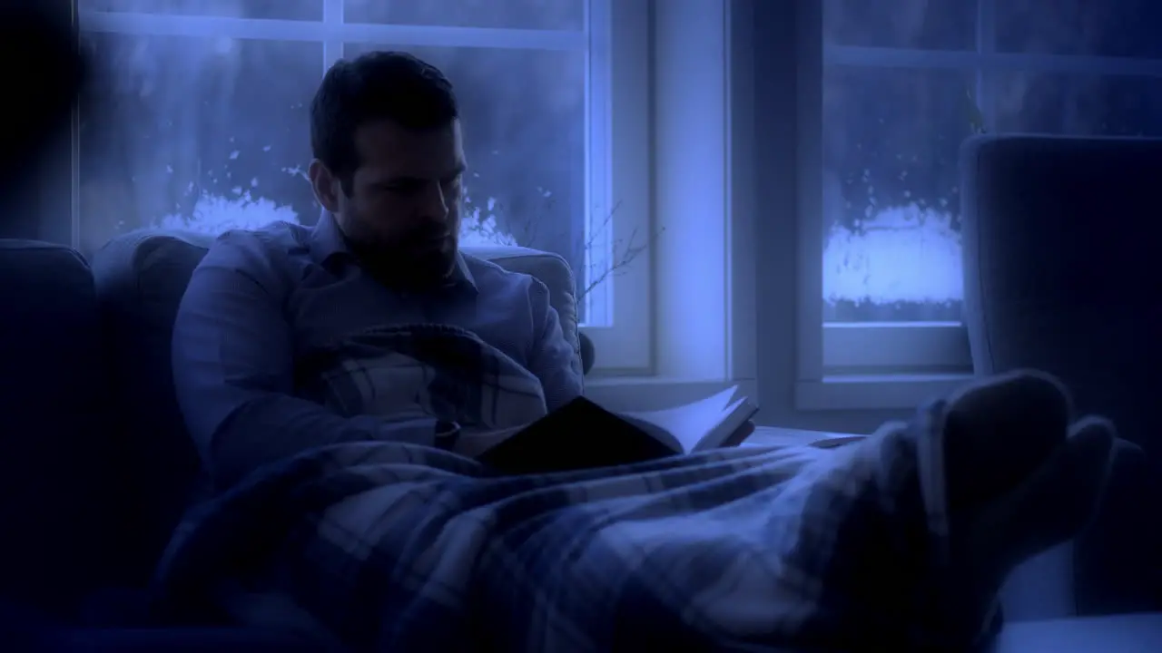 Man on couch reading book in moonlight