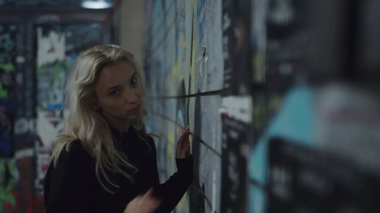 City girl moving body near building wall in urban area at night