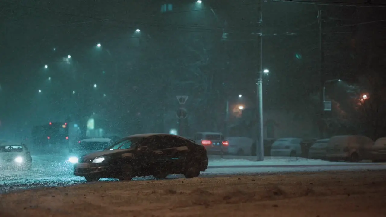 Car driving away in the city on a frosty winter night during a blizzard super slow motion teal and orange colors