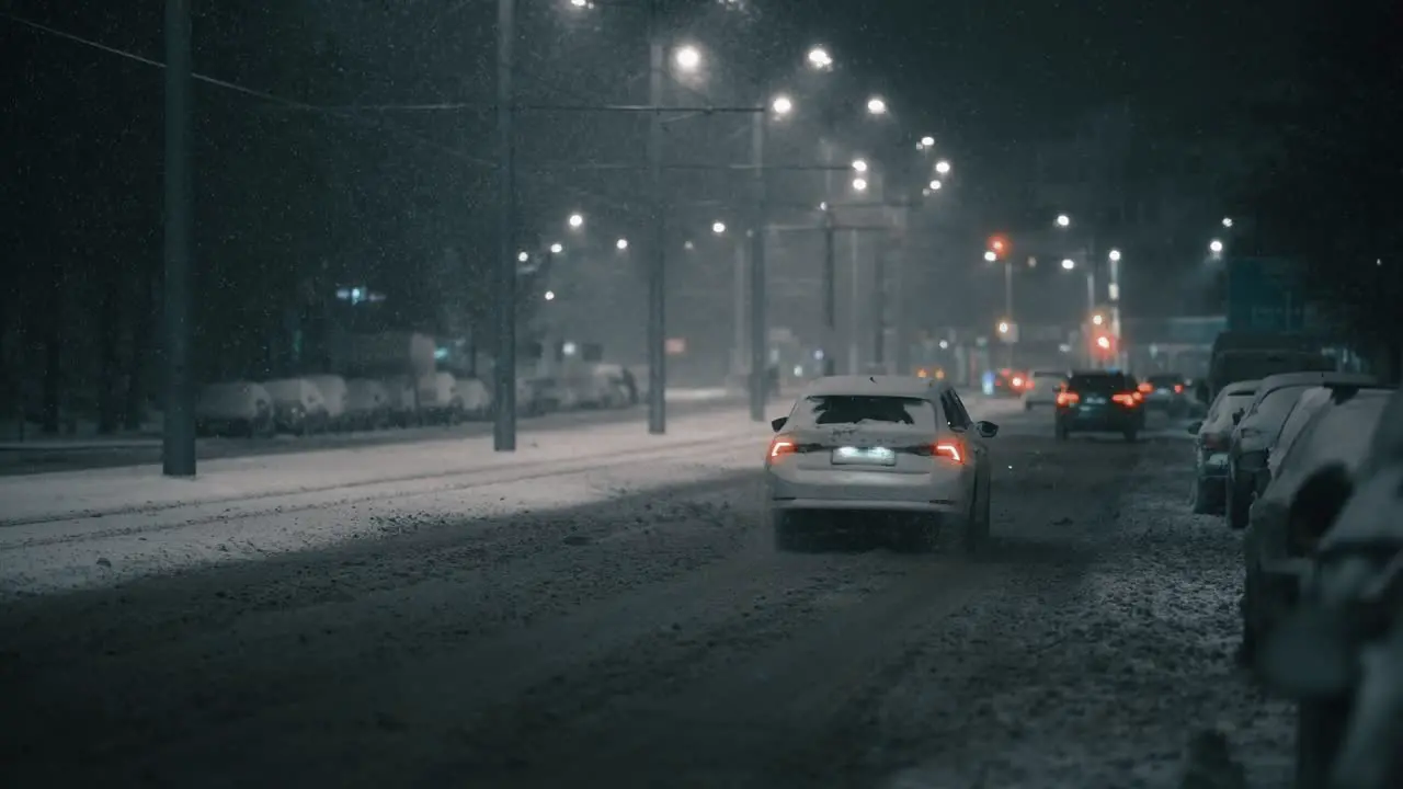 Car driving away in the city on a frosty winter night during a blizzard super slow motion