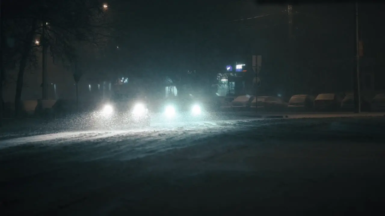 Cars driving in the city on a frosty winter night during a blizzard super slow motion