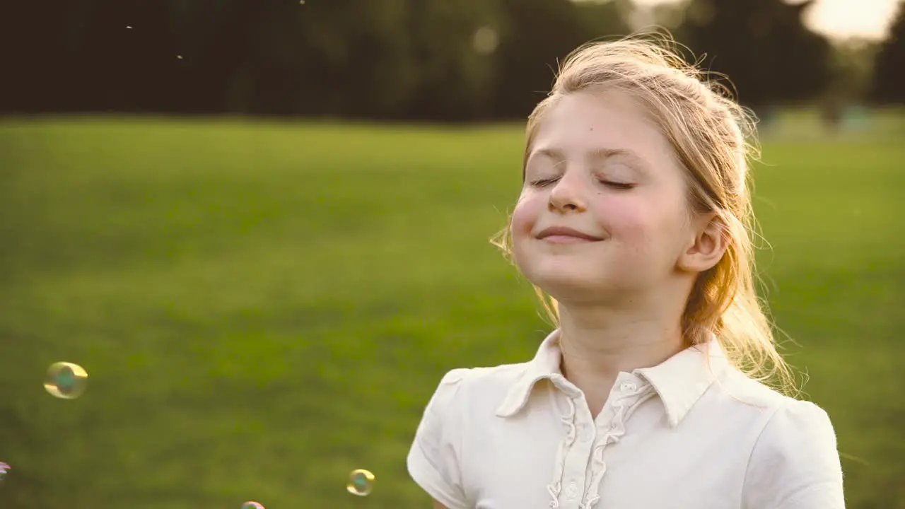 Retrato De Una Linda Niña Rubia Con Los Ojos Cerrados Sonriendo Rodeada De Burbujas De Jabón En El Parque 2