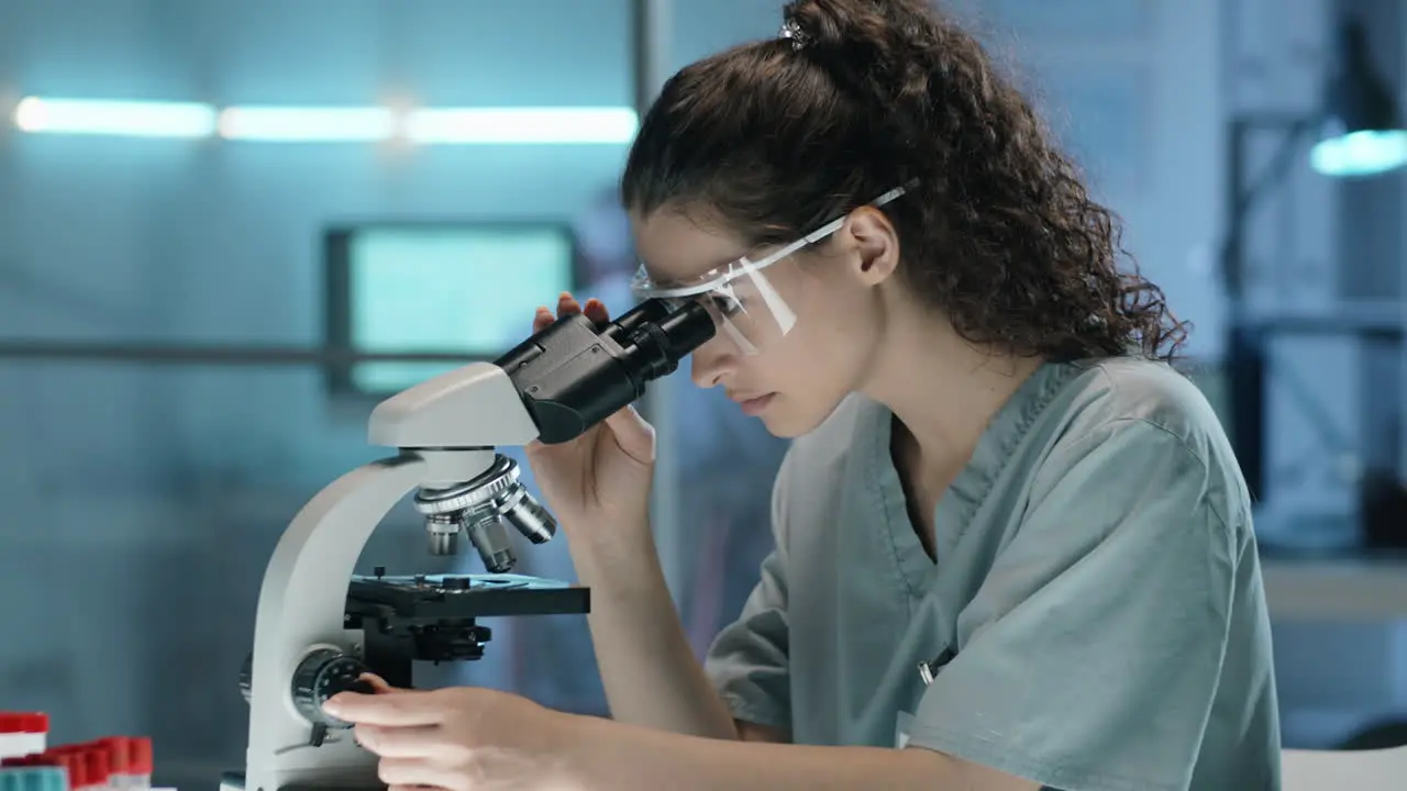 Joven Científica Usando Microscopio Y Tomando Notas