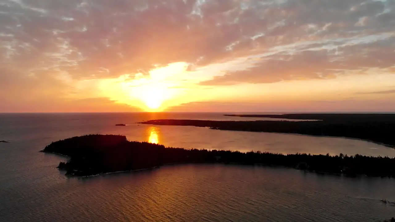 Aerial shot over great lake and peninsula during golden sunset with clouds