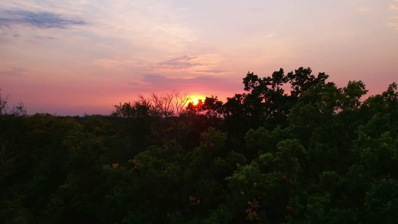 Sunset over woods and trees next to a small village in Germany Saxony Droneshot