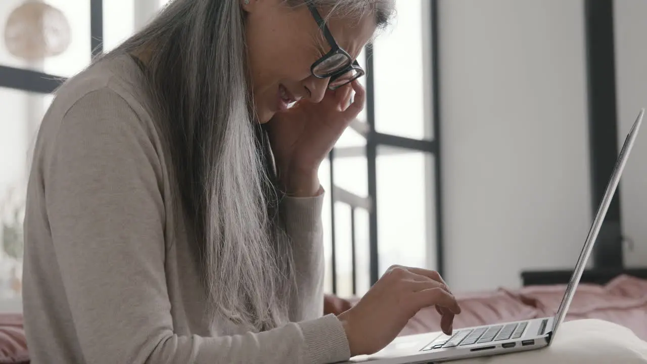 Mujer De Mediana Edad Con Dolor De Cabeza Mientras Trabaja En Una Laptop Sentada En Un Sofá En Casa