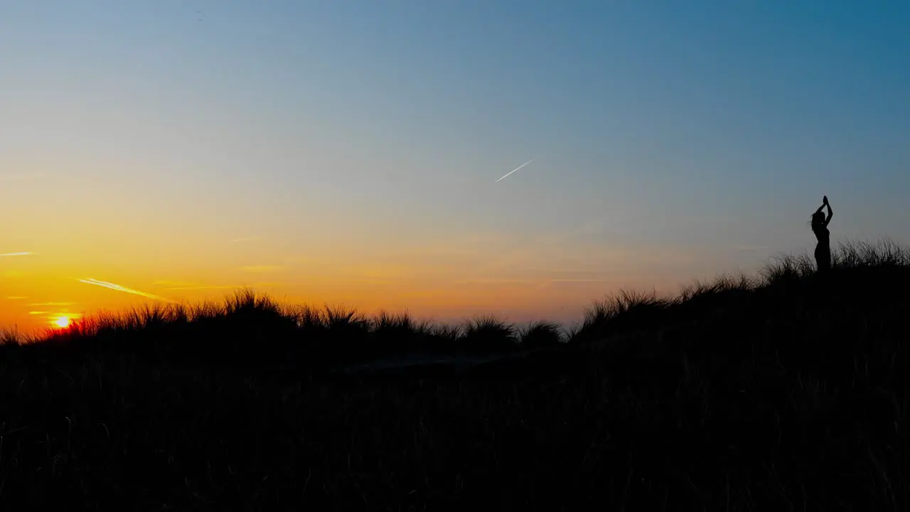 Side view of woman practising yoga in nature while sunset