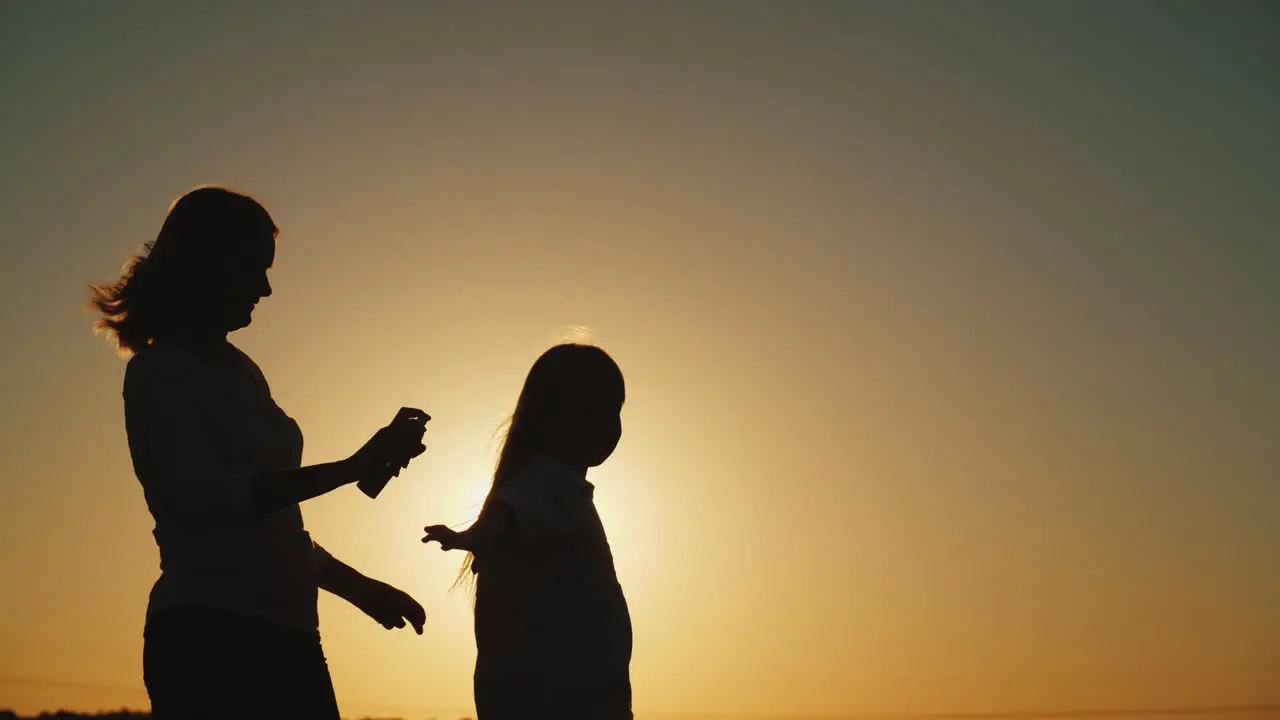 A Woman Spray Spray From Insects On Her Daughter Silhouettes At Sunset Rest Without Harmful Insects 