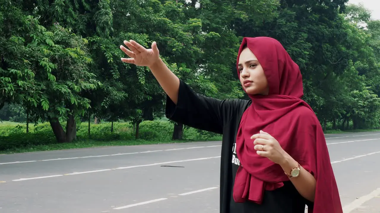 Slow motion of a young smiling Afghan girl in a black and red dress standing on the side of the road waiting for public transport to go back home