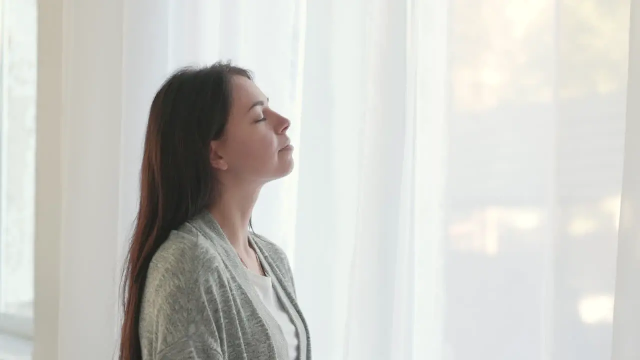 Frau Mit Geschlossenen Augen Atmet Tief Durch Während Sie Morgens Zu Hause Am Fenster Steht 1