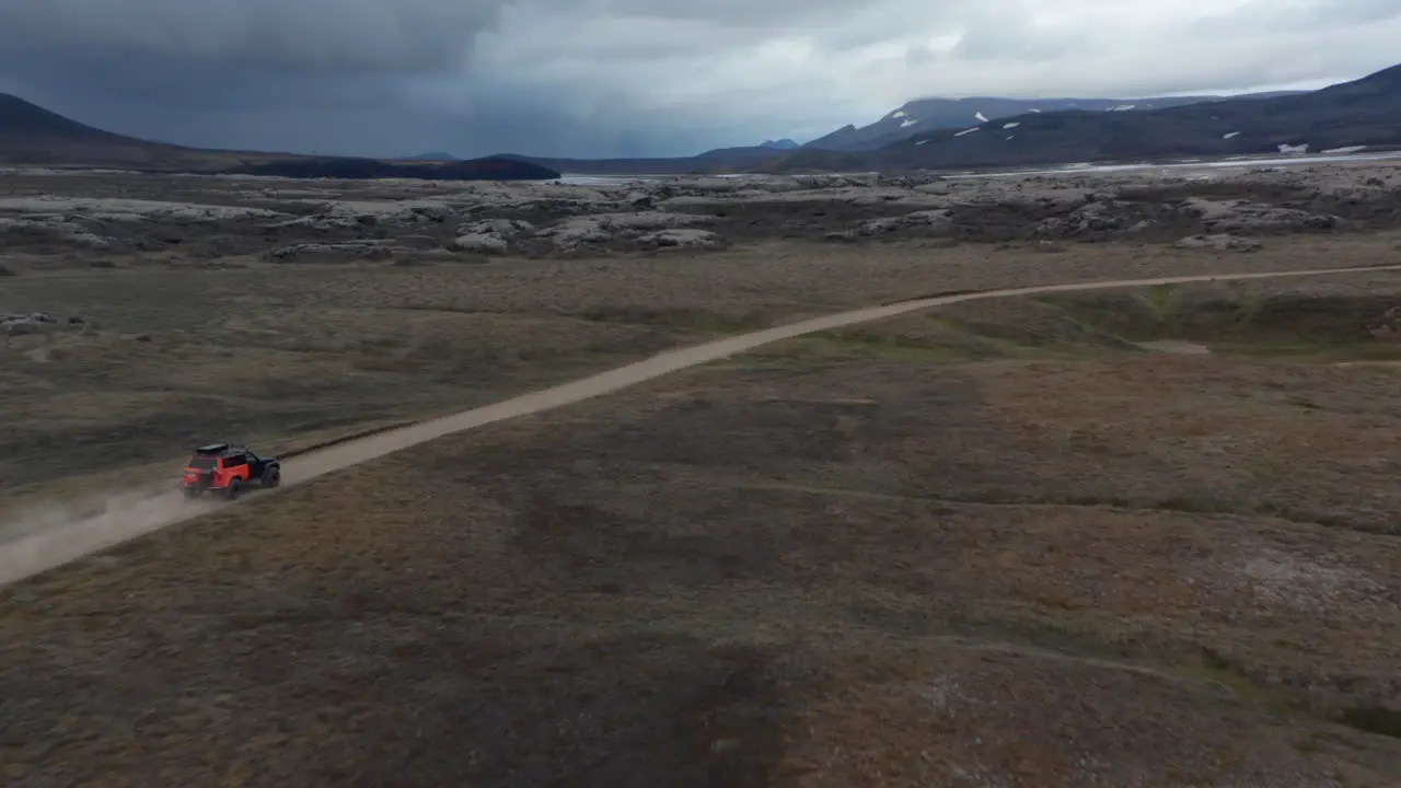 Drone view 4x4 jeep car driving speeding on dirt road in icelandic countryside Safety and insurance Birds eye adventurous people traveling wild desert in Iceland driving offroad