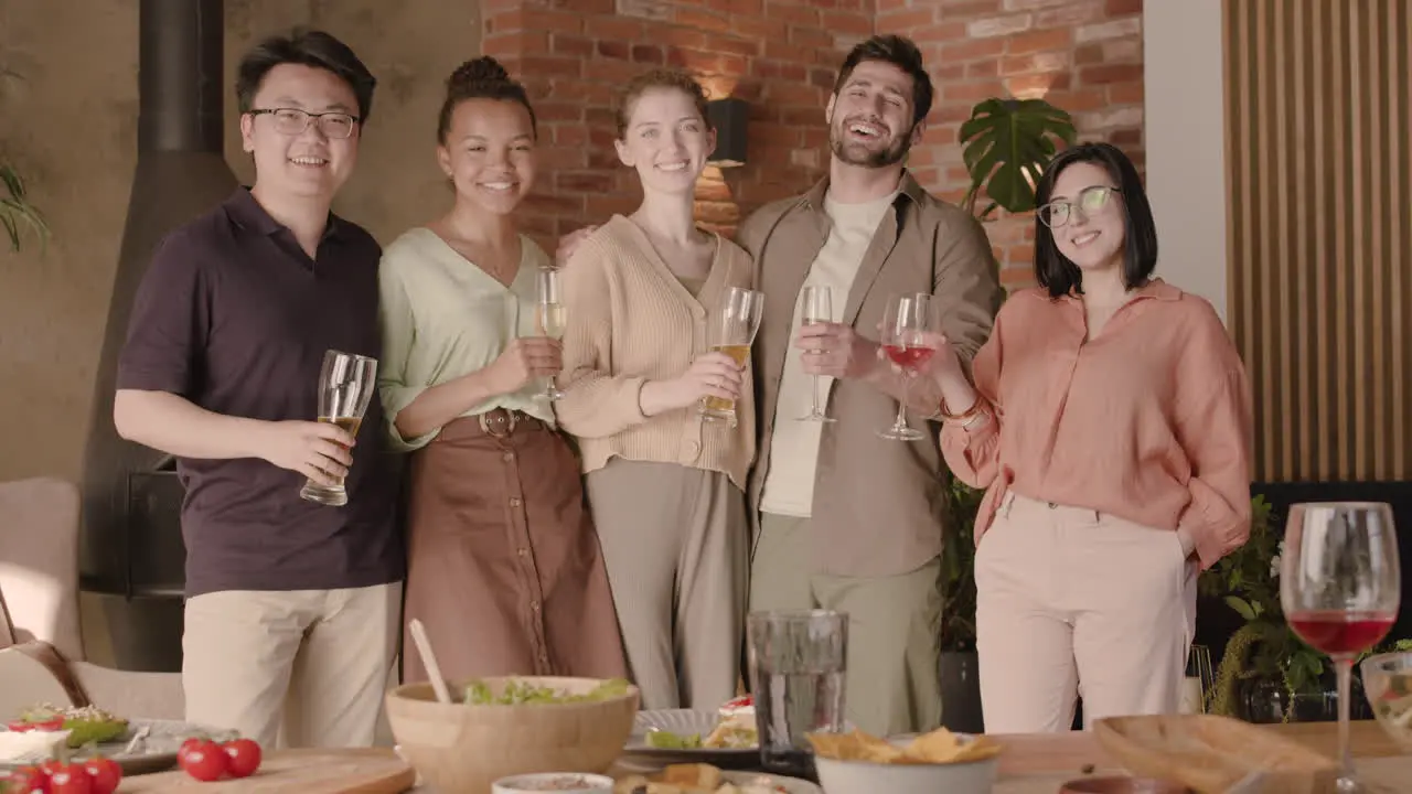 A Multicultural Group Of Friends Looking At The Camera And Smiling At A Dinner Party