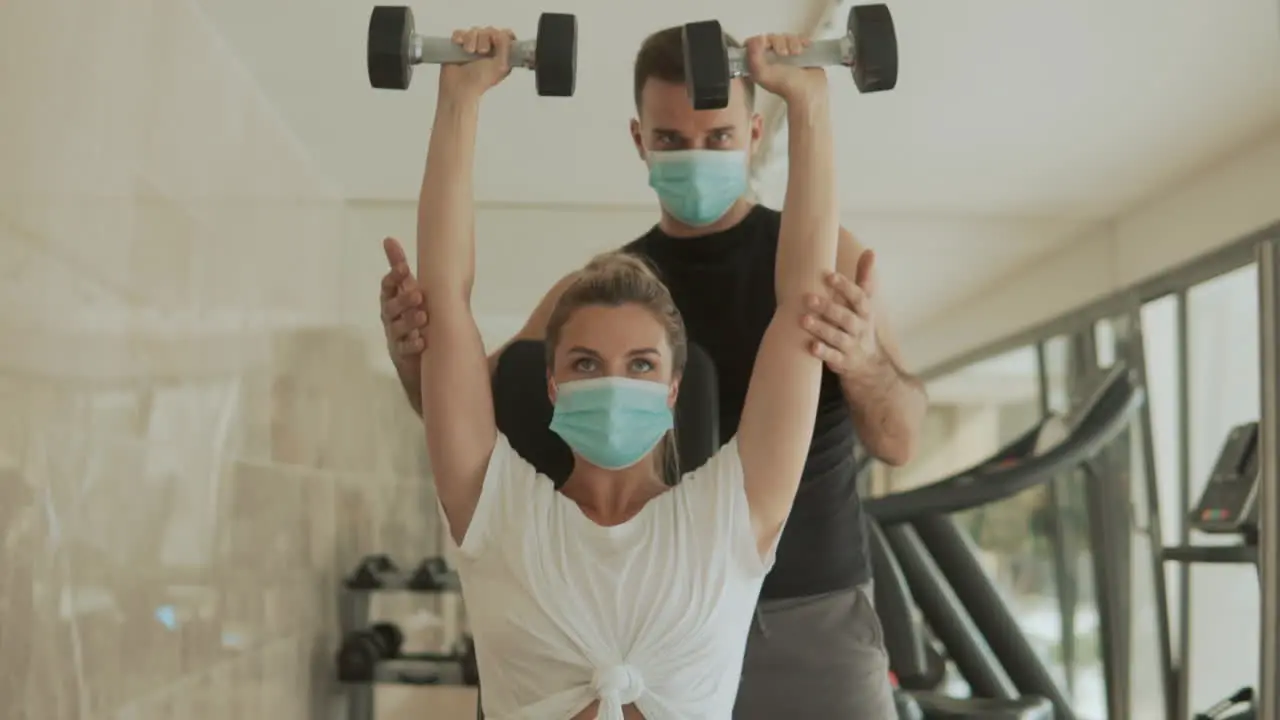 Athlete Woman Lifts Weights And Man With Face Mask Exercising In The Gym