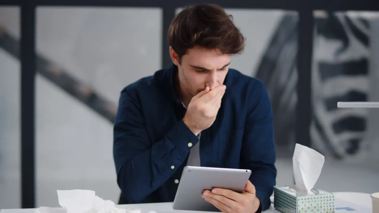 Focused business man reading pad in office Ill man getting flu in office