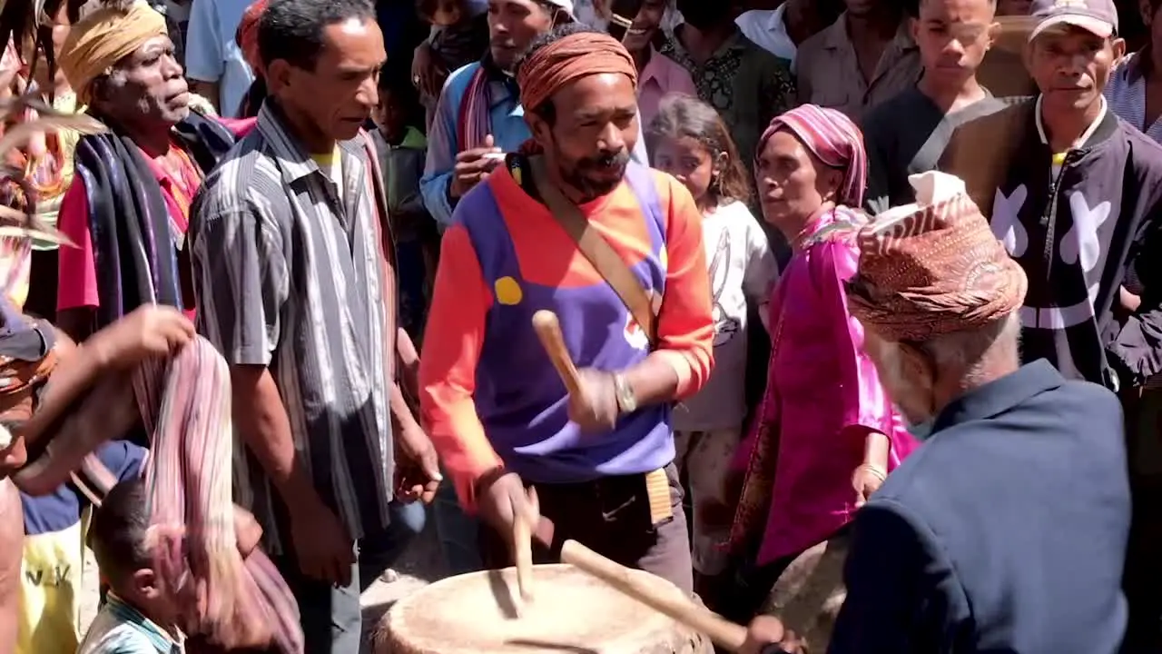 A gathering of Timorese people at a traditional cultural welcome ceremony playing the drums singing and dancing in East Timor Southeast Asia