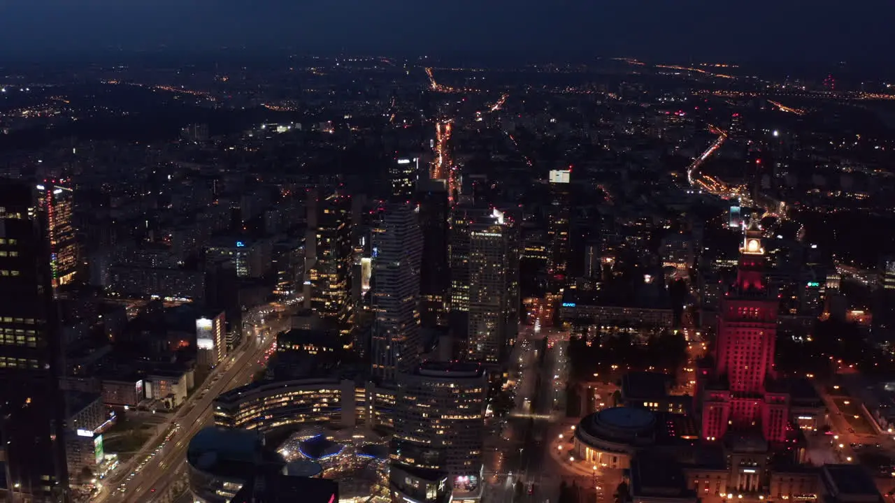 Slide and pan shot of city at night Aerial panoramic footage with Zlote Tarasy shopping mall and Palace of Culture and Science Warsaw Poland