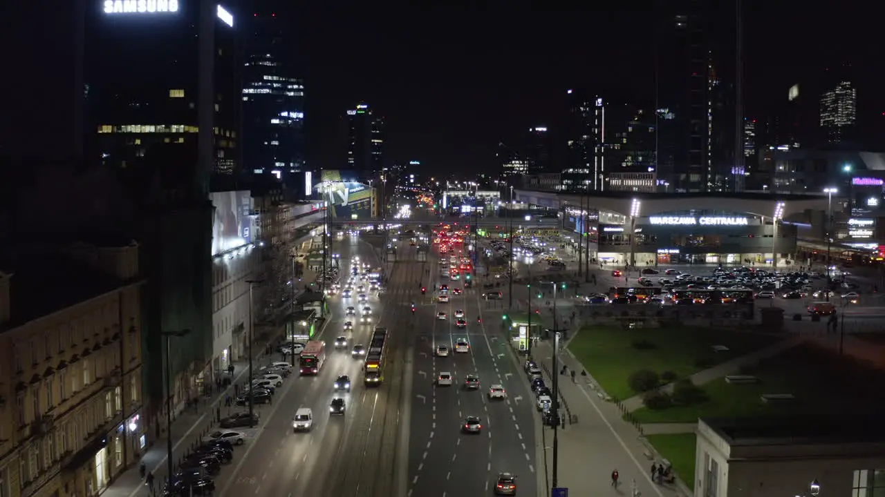 Rising footage of heavy traffic in city centre at night Wide multilane road leading between high rise buildings and train station Warsaw Poland