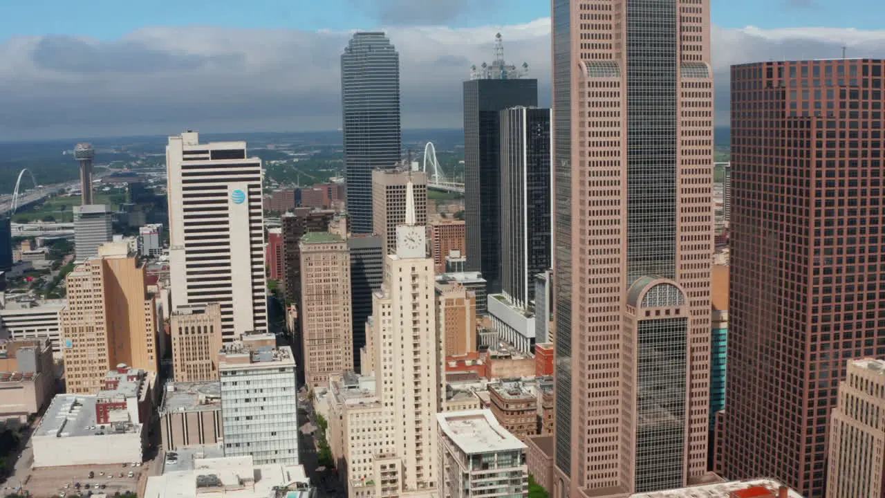 Aerial panning view tall modern office buildings downtown Drone moving around Mercantile National Bank Building with tower and big clock Dallas Texas US