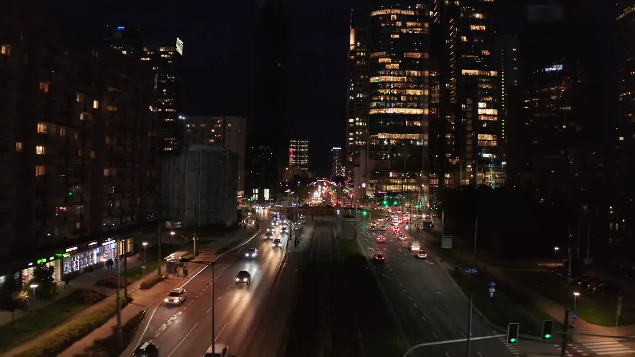 Fly above multilane road leading through large town Cars driving in street and intersection Night city scene Warsaw Poland