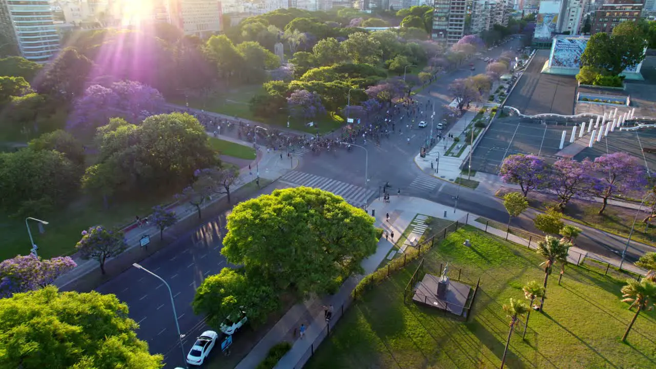 Dolly in aerial view of a group of cyclists with an epic shot of the sun's rays square full of trees around Recoleta neighborhood