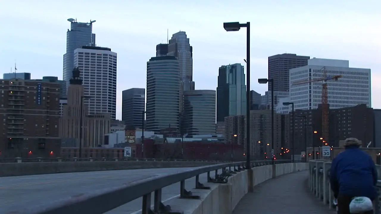 Cars And A Bicyclist Cross A Bridge Into The City