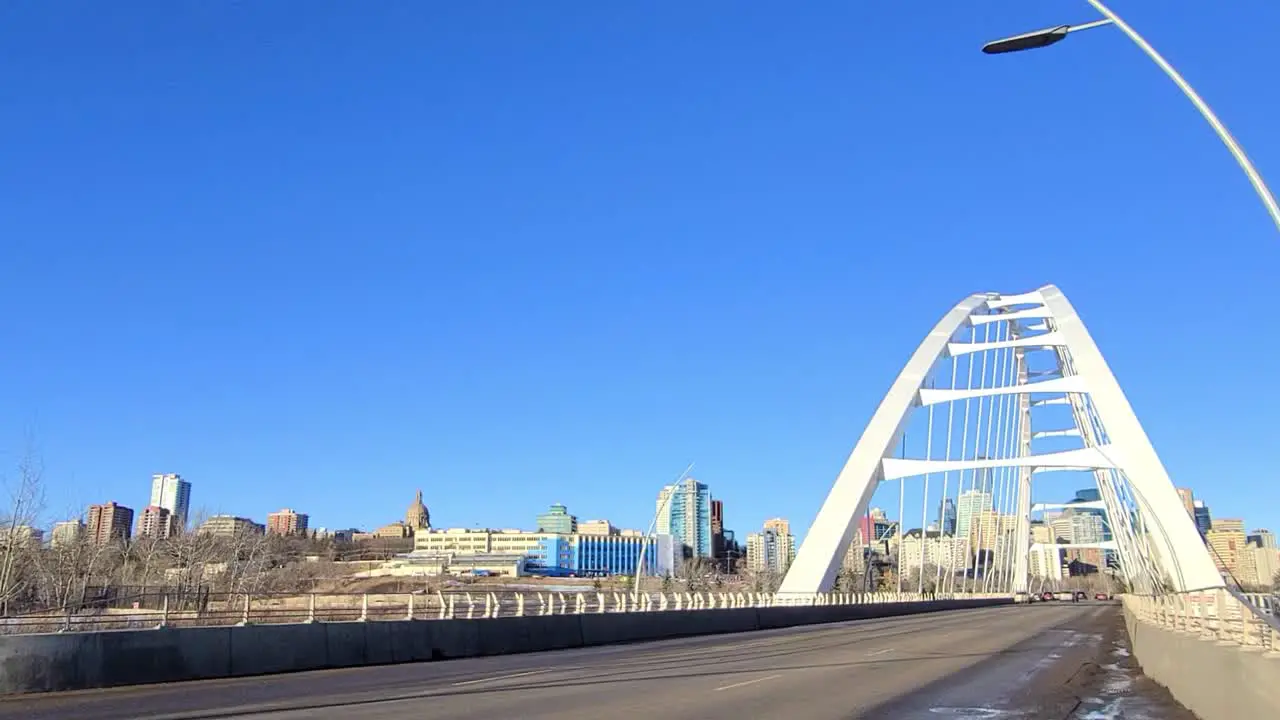 closeup entrance of the white modern Walter Dale Tied-arch bridge over the North Saskatchewan River with a skyline ridge of the Legislature the power plant next to the Alberta Treasury Board 1-2